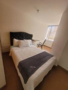um quarto com uma cama com uma cabeceira preta e uma janela em ARENA PARK em Bogotá