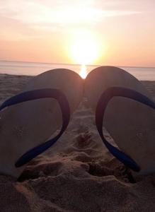 two surfboards in the sand with the sun in the background at Cashewnut Tree Resort in Ko Lanta