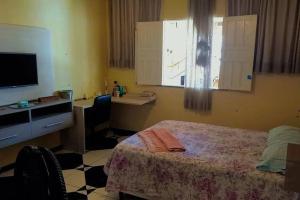 um quarto com uma cama, uma secretária e uma televisão em Riverside house em Barra dos Coqueiros