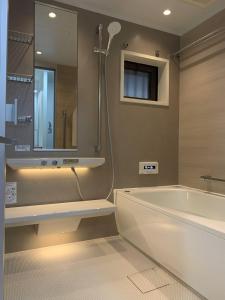 bagno con vasca, doccia e specchio di Sakura Retreat Ryokan- Haneda Gateway-澪 a Tokyo