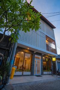 a building with a store front with a tree at Alba Inn Sanur by SooBali in Sanur