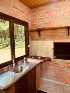 eine Küche mit Spüle und Ziegelwand in der Unterkunft Morro Azul chalés in Timbó