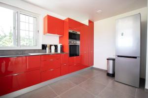 eine Küche mit roten Schränken und einem Kühlschrank in der Unterkunft Séjour Glycéria: Villa Canne à Sucre in Le Marin