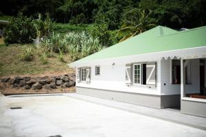 ein kleines weißes Haus mit grünem Dach in der Unterkunft Séjour Glycéria: Villa Canne à Sucre in Le Marin