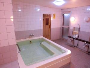 a bath tub in a bathroom with a shower at ホテル青木 in Ina