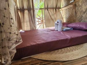 uma cama com um animal de toalha sentado em cima dela em BICE Camp Bucana Beach em El Nido
