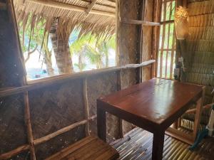 uma mesa de madeira e banco num quarto com uma janela em BICE Camp Bucana Beach em El Nido
