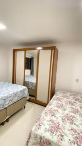 a bedroom with two beds and a mirror at Casa praia 99 in Serra