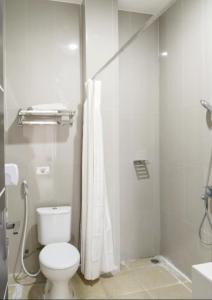 y baño blanco con aseo y ducha. en KHARIZ HOTEL en Bukittinggi