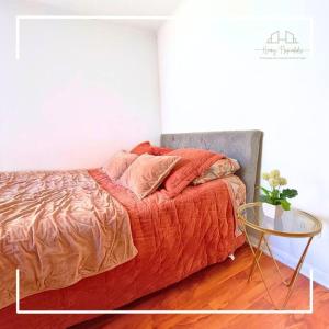 ein Bett mit einer orangefarbenen Bettdecke und einem Tisch in der Unterkunft Dpto en el centro de la ciudad in Santiago