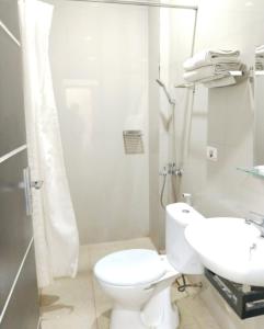 a white bathroom with a toilet and a sink at KHARIZ HOTEL in Bukittinggi