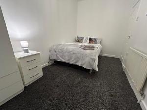 um pequeno quarto com uma cama e uma cómoda em Comfortable, spacious 2 Bedroom house close to Etihad Stadium em Stalybridge