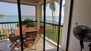 a balcony with a table and chairs and the ocean at Bas du Fort - Magnifique vue mer - Pieds dans l'eau - Citerne d'eau - Bord de plage in Le Gosier +6 photos