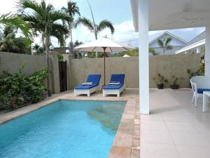 a swimming pool with two blue chairs and an umbrella at Kartika Villas in Lovina