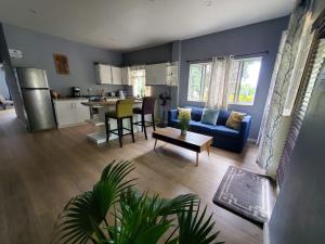 a living room with a blue couch and a kitchen at NATURES BLISS-ISLANDERS in Choiseul