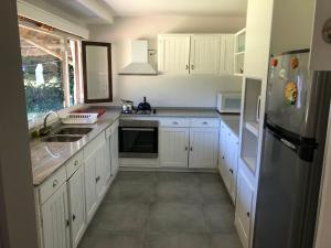 eine Küche mit weißen Schränken, einer Spüle und einem Kühlschrank in der Unterkunft Villa Carolina in Punta del Este