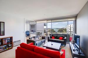 a living room with a red couch and a tv at The Bay Bach - Napier Holiday Apartment in Napier