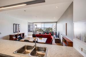 a kitchen with a sink and a living room at The Bay Bach - Napier Holiday Apartment in Napier