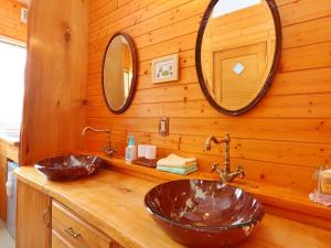 a bathroom with two sinks and two mirrors on a wooden wall at コテージ野の香 in Omachi