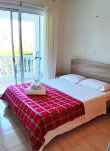 a bedroom with a bed with a red plaid blanket at SEA CAVES suite in Peyia