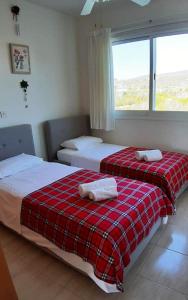 two beds in a room with a red plaid blanket at SEA CAVES suite in Peyia