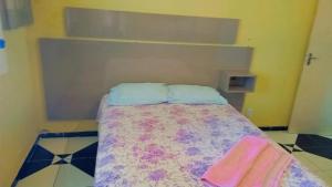 ein kleines Schlafzimmer mit einem Bett mit einer farbenfrohen Tagesdecke in der Unterkunft Riverside house in Barra dos Coqueiros