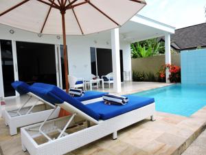 a pool with a bed and an umbrella next to a pool at Kartika Villas in Lovina