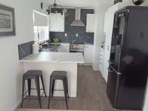 a kitchen with white counters and a black refrigerator at Omanu Cottage in Mount Maunganui +29 photos
