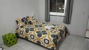 un letto con piumone e cuscini in una camera da letto di Ytamãní l apartamentos a Santa Cruz Cabrália