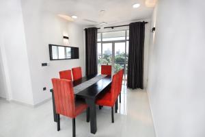 a dining room with a black table and red chairs at BNB RESIDENCIES MOUNT LAVINIA 2 in Mount Lavinia
