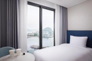 a hotel room with a bed and a large window at Citadines Connect Hari Busan in Busan