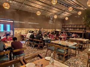 un grupo de personas sentadas en mesas en un restaurante en Mango Leaf Lake Resort en Pune