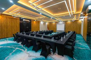 Nunia Tamansari Hotel في Kumprung: قاعة اجتماعات مع طاولة وكراسي كبيرة