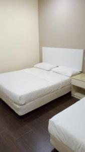 2 camas en una habitación con sábanas blancas en NEW D SOHO HOTEL GOMBAK en Batu Caves