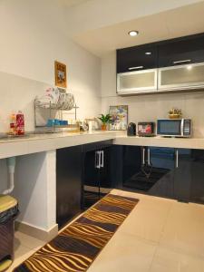 a kitchen with black cabinets and a counter top at HomeStay De’Viana NMS Residence in Kota Bharu