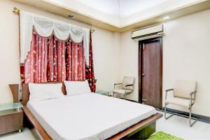 a bedroom with a bed and two chairs and a window at OYO Hotel M & c in Patna