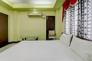 a bedroom with a large white bed and a chair at OYO Hotel M & c in Patna