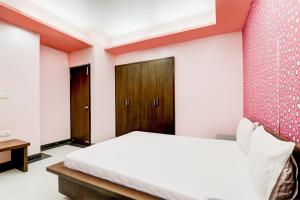 1 dormitorio con cama blanca y pared roja en OYO Hotel M & c, en Patna