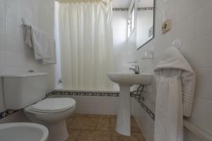 Baño blanco con aseo y lavamanos en Hotel San Andres, en Jerez de la Frontera