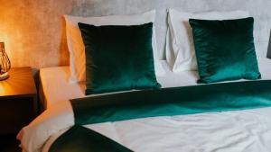 a bed with green and white pillows on it at Mazurska Zatoka in Łukta