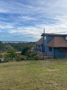 a blue house on top of a grass field at Casa Sra Oti, Tipo Hostal con vista al mar Puerto Montt - CHINQUIHUE in Puerto Montt