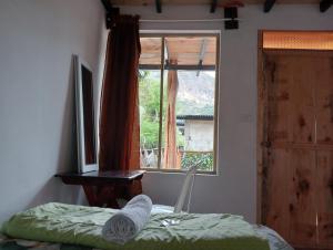 Dormitorio con ventana, cama y escritorio en Cabaña Tzanjuyu en San Juan La Laguna