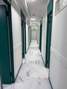 a corridor of an office with marble floors and green doors at Stay 2002 in Seoul