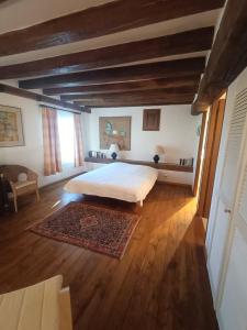 Schlafzimmer mit einem großen weißen Bett und Holzböden in der Unterkunft Les Essarts pour 10+6 personnes sur 2 maisons in Châtillon-sur-Indre