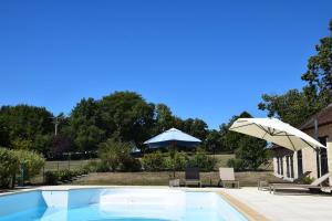 a swimming pool with an umbrella and chairs and tables at Les Essarts pour 10+6 personnes sur 2 maisons in Châtillon-sur-Indre