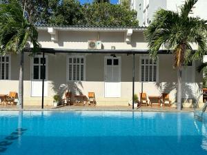 a swimming pool with chairs and a house at Pharos Guesthouse in Mui Ne