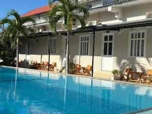 a large blue swimming pool in front of a building at Pharos Guesthouse in Mui Ne