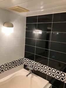 ein Badezimmer mit einem Waschbecken und einer schwarz-weiß gefliesten Wand in der Unterkunft Hotel Angel (Adult Only) in Yokohama