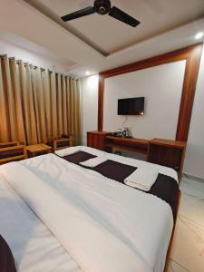 Hotel DC Hills Rishikesh في ريشيكيش: غرفة نوم بسرير كبير مع مروحة سقف