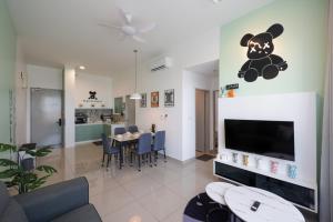 a living room with a television and a dining room at Bear Paw Retreat Cityview Apartment Amber Cove in Melaka